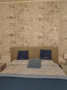 a bedroom with a bed with blue pillows and floral wallpaper at Oasi di pace in Rocca deʼGiorgi