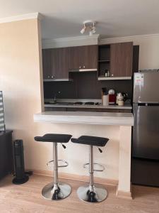 a kitchen with two bar stools and a refrigerator at Departamento Los Poetas in Temuco +21 photos