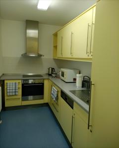 a small kitchen with yellow cabinets and appliances at Pension Am Seeberg in Alt Zeschdorf
