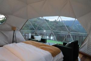 a bedroom with a bed and a large window at The Kamcha Geodesic dome & Homestay in Bomdila