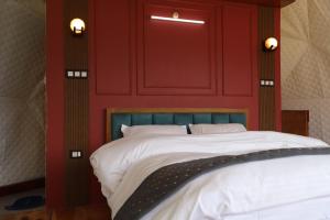 a bedroom with a red wall with a bed at The Kamcha Geodesic dome & Homestay in Bomdila