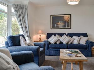 a living room with two blue couches and a table at Hillside Cottage in Keswick