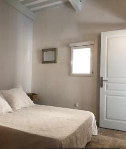ein weißes Schlafzimmer mit einem Bett und einem Fenster in der Unterkunft Au coeur de la Venise Povençale in LʼIsle-sur-la-Sorgue