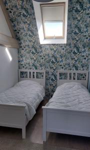 2 bedden in een slaapkamer met bloemenbehang bij Sur Les Roches in Dracy-lès-Couches