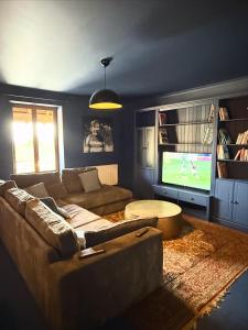 een woonkamer met een bank en een flatscreen-tv bij Sur Les Roches in Dracy-lès-Couches