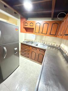 a kitchen with a stainless steel refrigerator and wooden cabinets at Hotel San Vicente in Medellín