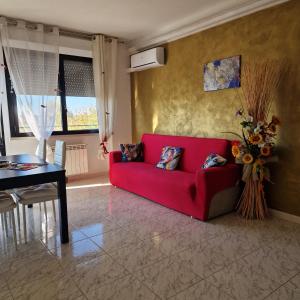 a living room with a red couch and a table at Appartamento Divino Tramonto in Altedo
