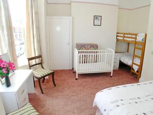 een slaapkamer met twee bedden en een kinderbedje en een kamer met een kinderbedje bij Mayflower in Cromer