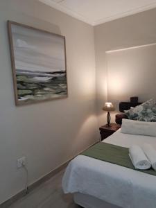 a bedroom with a bed and a picture on the wall at Klein Karoo Wegbreek in Oudtshoorn