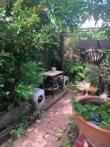 a garden with a table and a bench and trees at Palmhouse studio room in Bang Khen