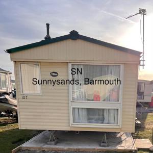 a small shed with the words sun sun sun sunsets and barnmut at Sandy Cove 50 in Llanddwywe