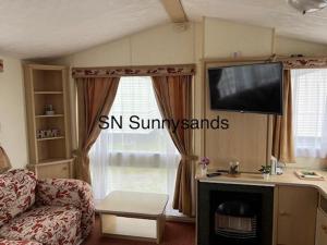 a living room with a couch and a tv at Sandy Cove 50 in Llanddwywe