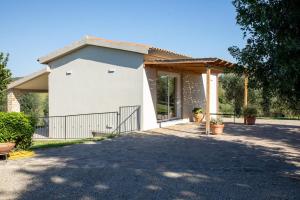 a white house with a gate and a porch at Il giardino di Magliano in Magliano in Toscana +12 photos