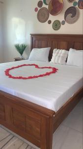 a bed with a white mattress with a red flower on it at Maya, Entire Apartment, Mbour, 3 air-conditioned bedrooms in Mbour