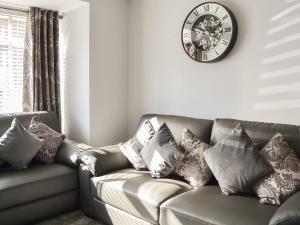 a living room with a couch with pillows and a clock at Lowey's Harbour Cottage in Bridlington
