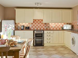 a kitchen with white cabinets and a table with a tableablish at The Stables- Osb in Penbryn +8 photos