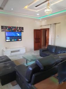 a living room with black leather furniture and a flat screen tv at Maya, Entire Apartment, Mbour, 3 air-conditioned bedrooms in Mbour
