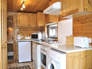 a kitchen with white appliances and wooden cabinets at Acorn Lodge - Burnside Park in Keswick +3 photos
