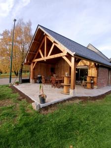 un grande padiglione in legno con tavolo e sedie di Le gîte Normand a Saint-Vaast-dʼÉquiqueville