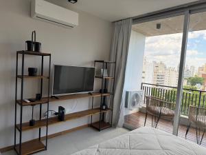 a bedroom with a flat screen tv and a balcony at Departamento Estudio Deluxe in La Plata
