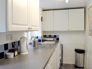 eine Küche mit weißen Schränken und einer Arbeitsplatte in der Unterkunft Drum And Monkey Cottage in Chapel en le Frith
