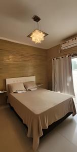 a large bed in a bedroom with a chandelier at Sobrado 2 amplo e confortável em condomínio in Corumbá