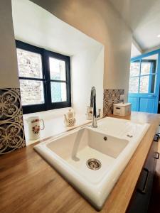 a white sink in a kitchen with two windows at Maison avec jardin aux Cabannes - Ariège in Les Cabannes +17 photos