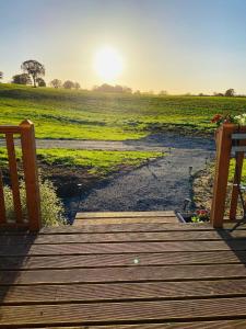 a wooden stairway leading to a field with the sun setting at La champ être in Neuville-sur-Sarthe