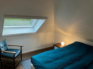a bedroom with a bed and a chair and a window at Tampico, Holiday Home at river Schelde in Hamme