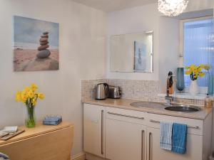 a kitchen with a counter with a sink and a stack of rocks at Salty Cottage in Newlyn