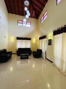 a living room with black couches and windows at Paradise Villa in Kandana