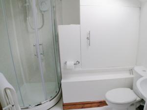 a white bathroom with a shower and a toilet at Jebel Kasr in Braithwaite +2 photos