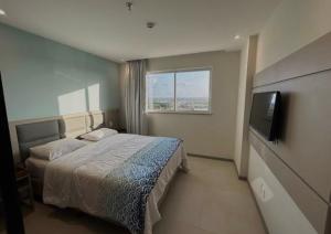 a bedroom with a bed and a flat screen tv at Apartamento Aqualand Salinas in Salinópolis