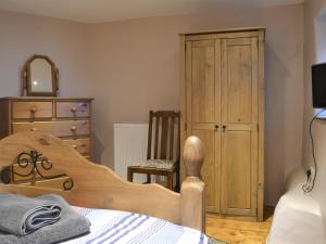 a bedroom with a bed and a dresser and a chair at The Stable in Criccieth