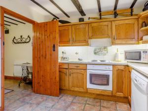 a kitchen with wooden cabinets and white appliances at Rafters Barn - E2064A in Runcton Holme +20 photos