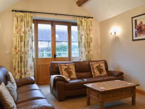a living room with a leather couch and a table at Shippon Cottage - E4299A in Halston