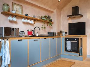 a kitchen with blue cabinets and a microwave at Olive in Kelsall +6 photos