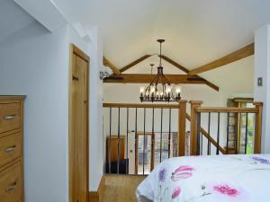 a bedroom with a bed and a chandelier at Little Barn in Gilwern +8 photos