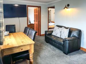 a living room with a leather couch and a table at Haddon Cottage - Uk40270 in Bakewell