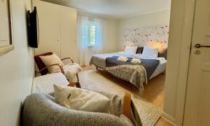 a bedroom with two beds and a chair and a couch at Strandlogiet Ljugarn in Ljugarn
