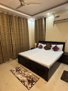 une chambre avec un lit avec des draps blancs et des oreillers dans l'établissement Shanti sadan, à Noida