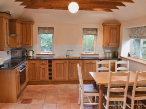 a kitchen with wooden cabinets and a table with chairs at The Old Stables in Cley next the Sea