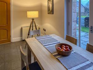 a dining room table with a bowl of fruit on it at Murton Cottage in East Ord