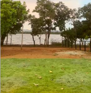 a field of grass with trees and a body of water at Hotel Pousada dos Ipês in Minaçu