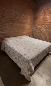 a bed in a room with a brick wall at Hotel Pousada dos Ipês in Minaçu