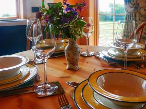 a table with plates and glasses and a vase with flowers at Stable Lodge At Greenacre in Bromyard