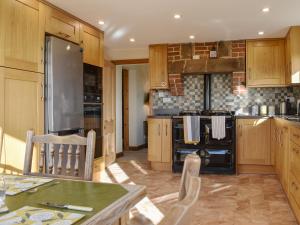 a kitchen with wooden cabinets and a stove top oven at Beech Cottage in Somersal Herbert