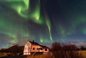 an old house with the aurora in the sky at Casa Hikari - Lofoten Retreat in Vestvågøya