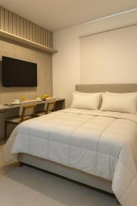 a bedroom with a white bed and a desk and a television at Bahia Flats Facility View in Salvador