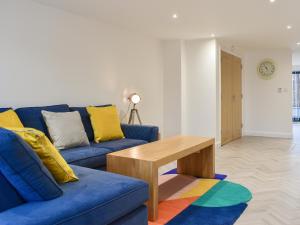 a living room with a blue couch and a wooden table at Little Trevose in Padstow